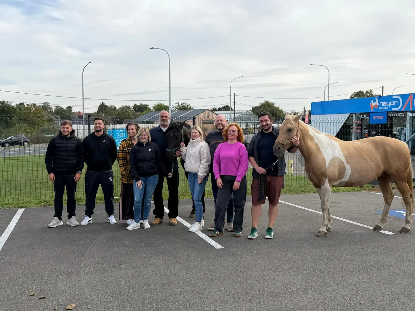 Une équipe pose avec deux chevaux lors d'une journée organisée sur un site partenaire